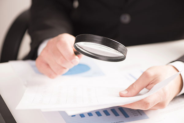 Businessman checking tablet with magnifying glass