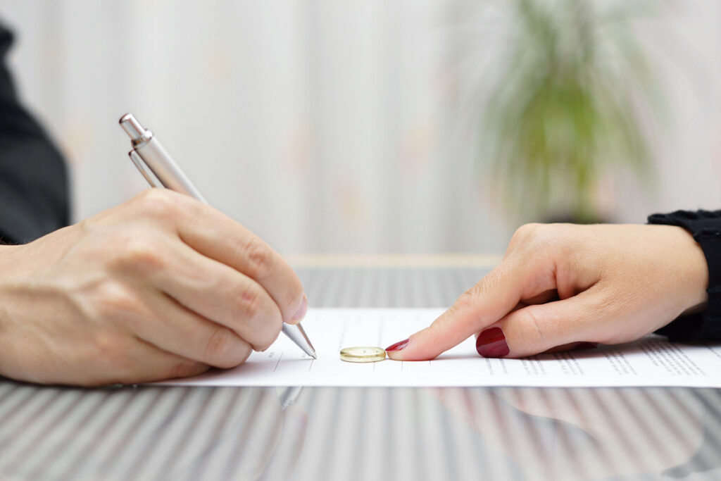 Husband signing divorce, woman push away ring